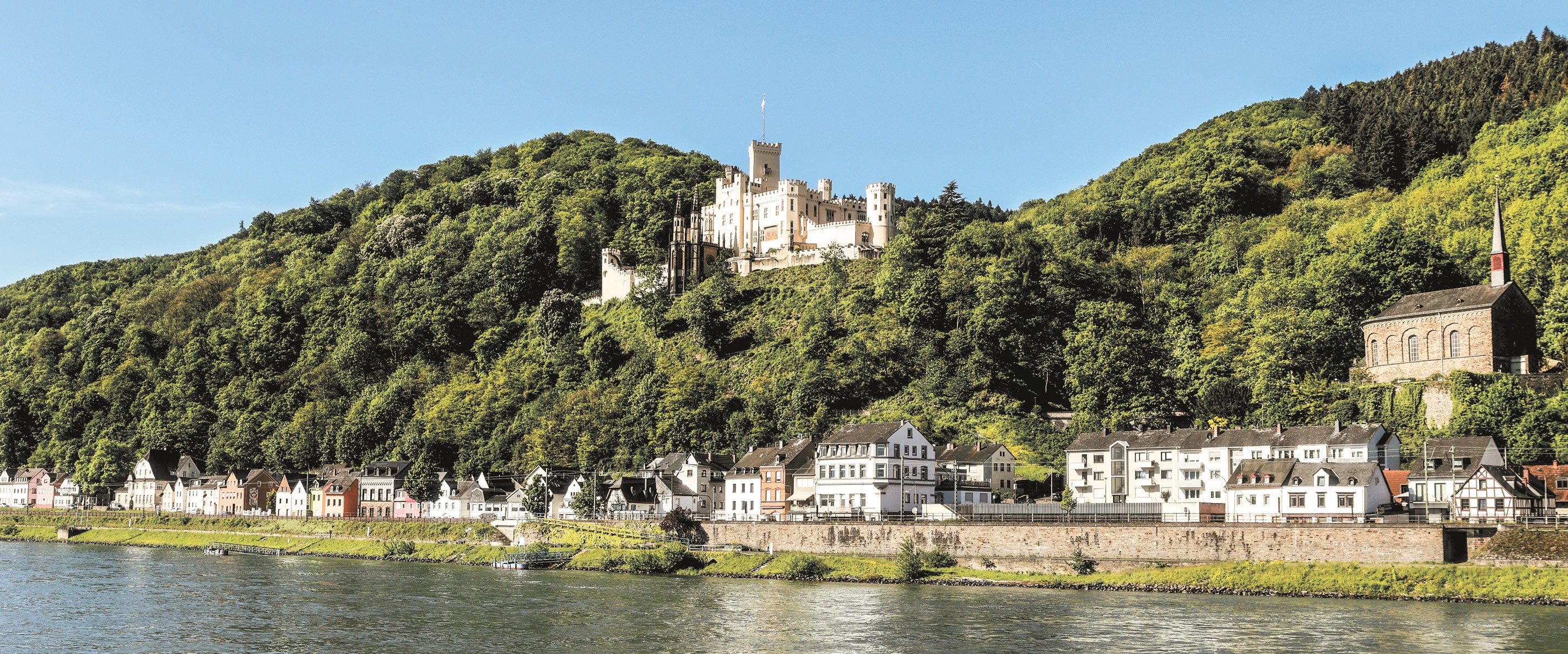Schloss Stolzenfels mit dem Ort Stolzenfels und dem Rhein im Vordergrund.