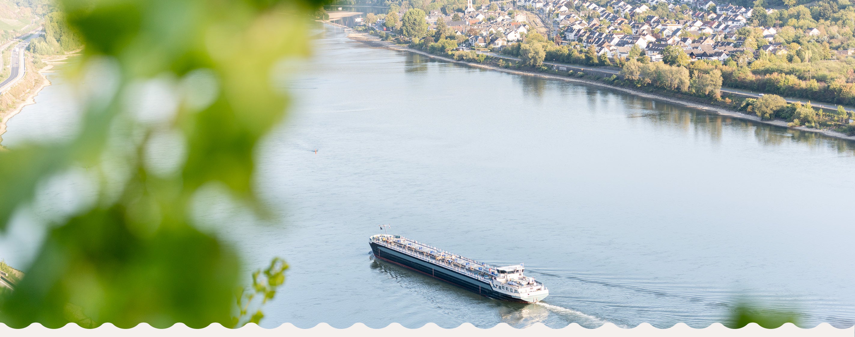 Blick von den Rheinhöhen bei Boppard auf den Rhein mit Frachtschiff und das gegenüberliegende Ufer mit Osterspai.